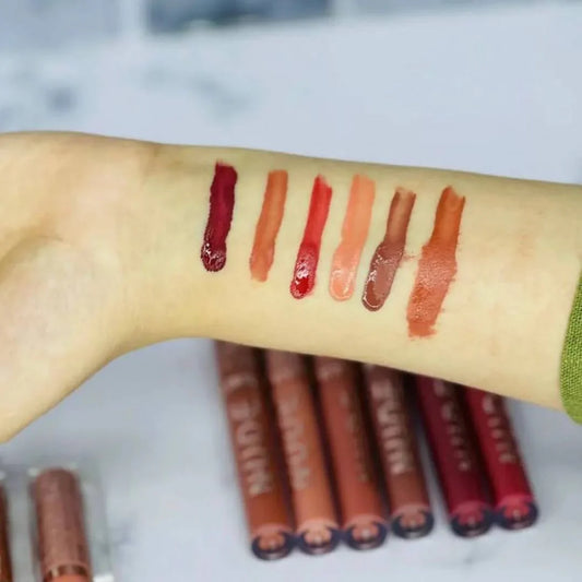 Lipstick swatches on a person's arm with lipsticks below