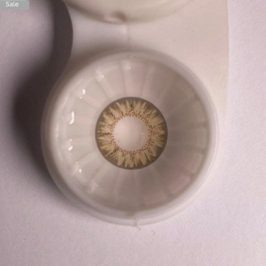 Close-up of a Pretty Seven Day Hazel contact lens in a case with a blurred background