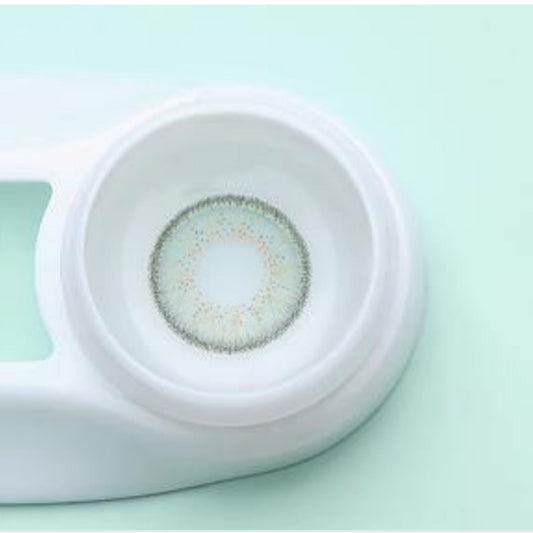 Rainbow green Contact lens in a white case on a light green background