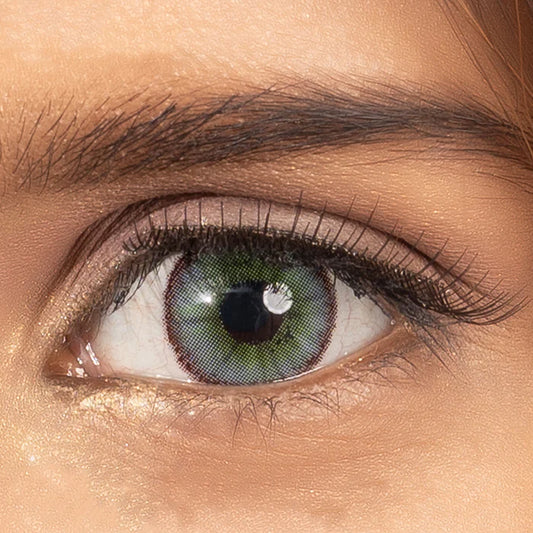 Close-up of a green eye wearing green lenses with detailed eyelashes and eyebrow