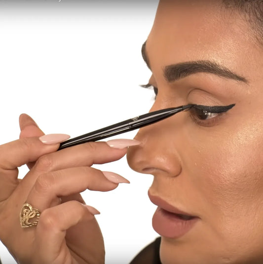 Person applying eyeliner with a brush on a white background at best price online sale in Pakistan