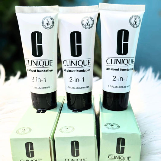 Three Clinique 2-in-1 foundation tubes on their boxes with a blurred natural background.