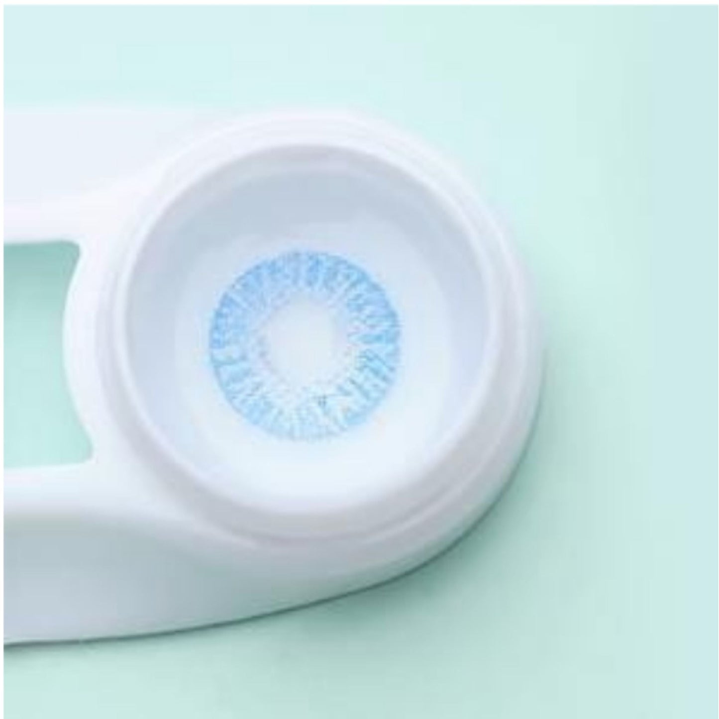 Close-up of a contact lens with a blue prescription on a light green background at best price online sale in Pakistan