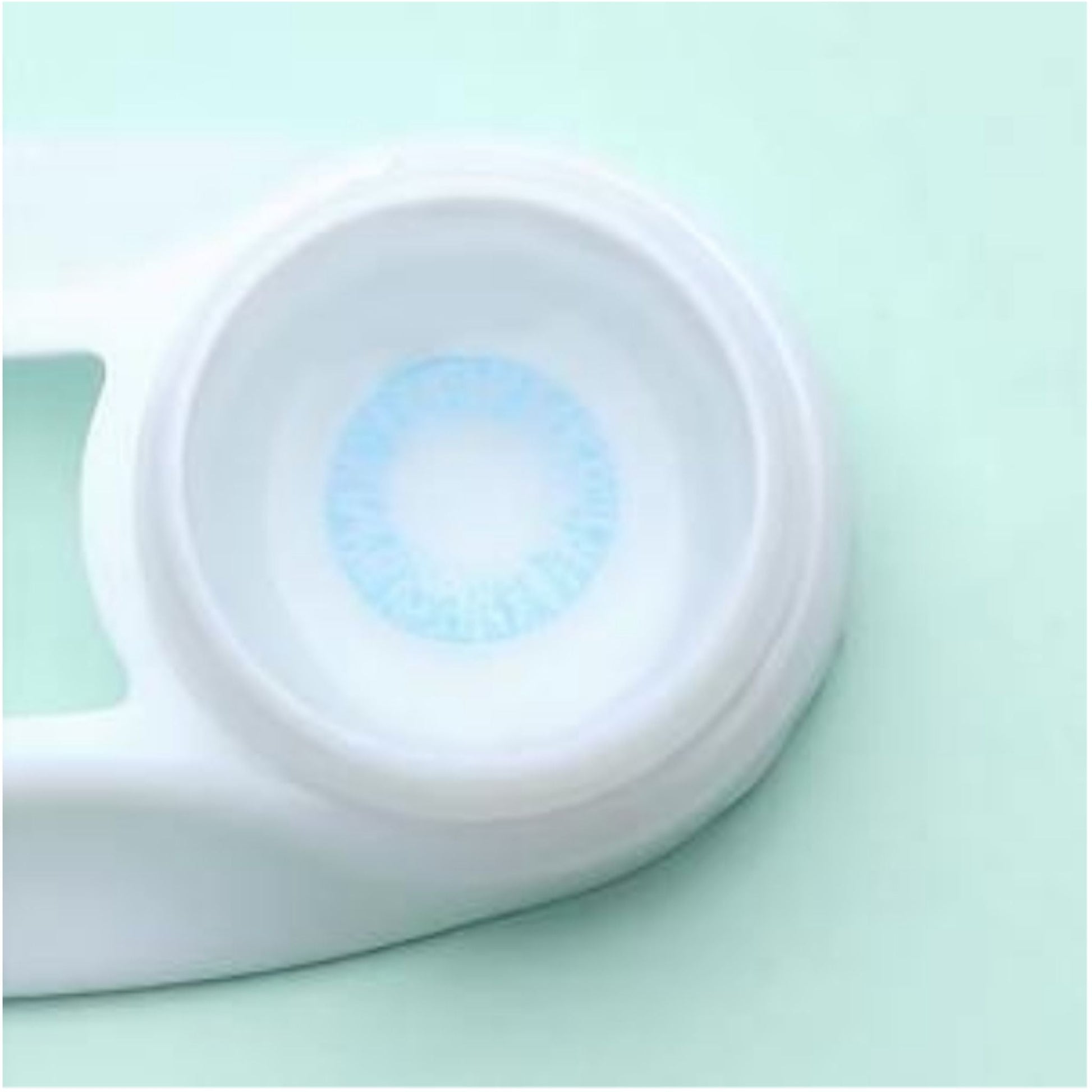 Close-up of a contact lens case with a blue contact lens on a light green background at best price online sale in Pakistan