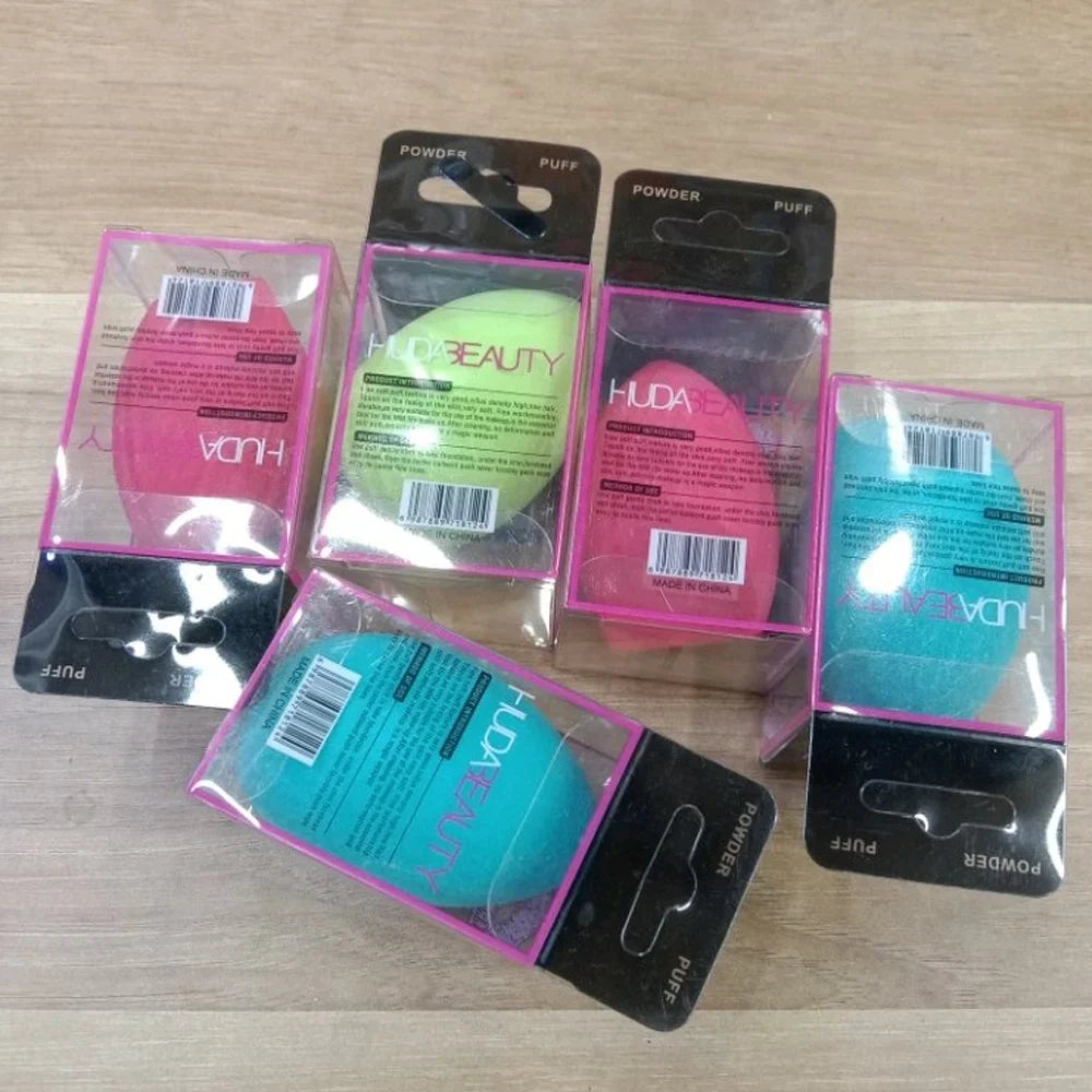 Packaged Huda Beauty powder puffs on a wooden surface at best price online sale in Pakistan