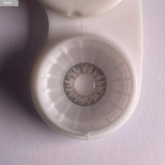 Close-up of a comfort contact gray_pretty_lens in a case on a light purple background