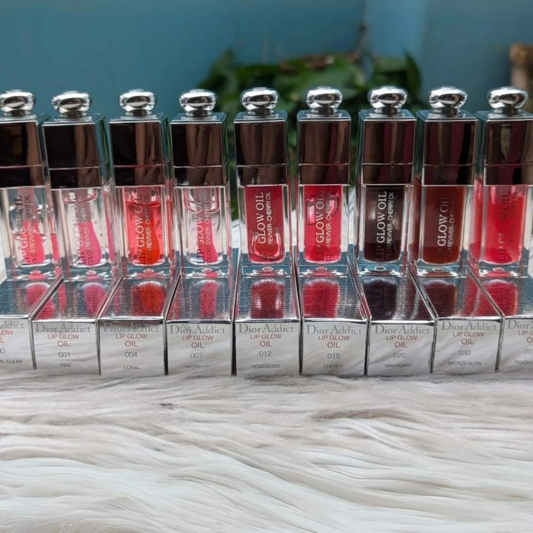Row of dior addict lip glow oil with visible branding on a textured surface.