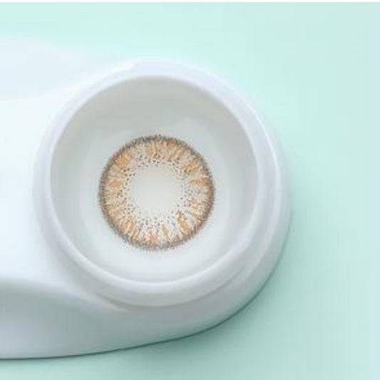 Close-up of a contact lens in a white container on a light green background at best price online sale in Pakistan