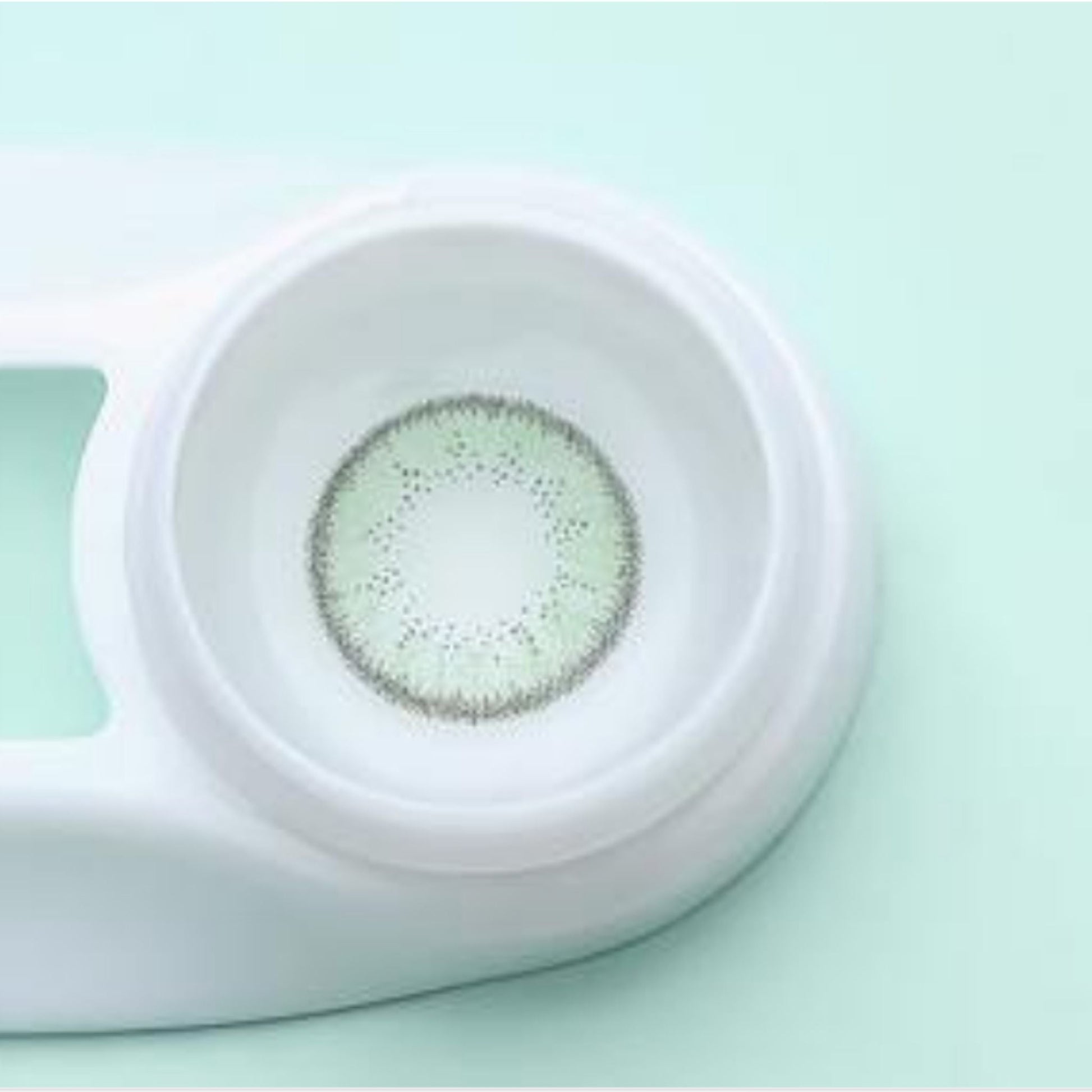 Contact lens case with a contact lens inside on a light green background at best price online sale in Pakistan
