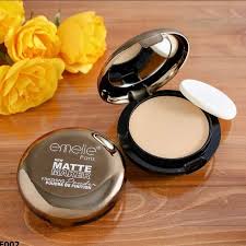 Makeup compact with powder and mirror on a wooden surface with yellow flowers.