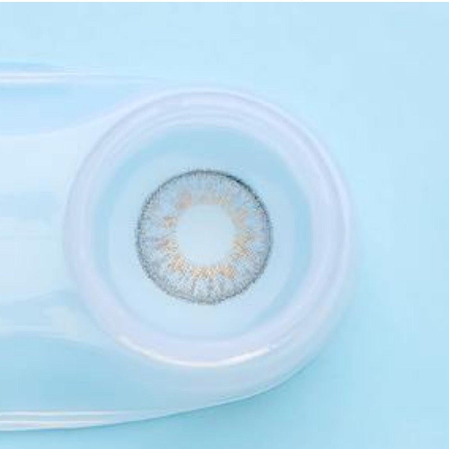 Gray contact lens in a container on a light blue background at best price online sale in Pakistan