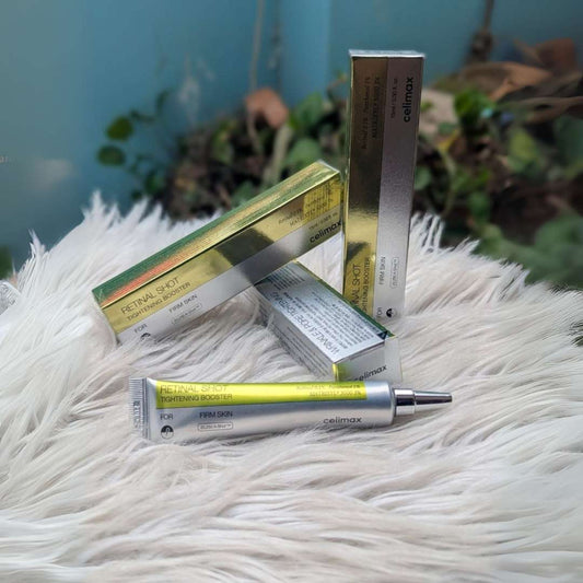 Cosmetic products including a tube and boxes on a fluffy white surface with a blurred natural background.