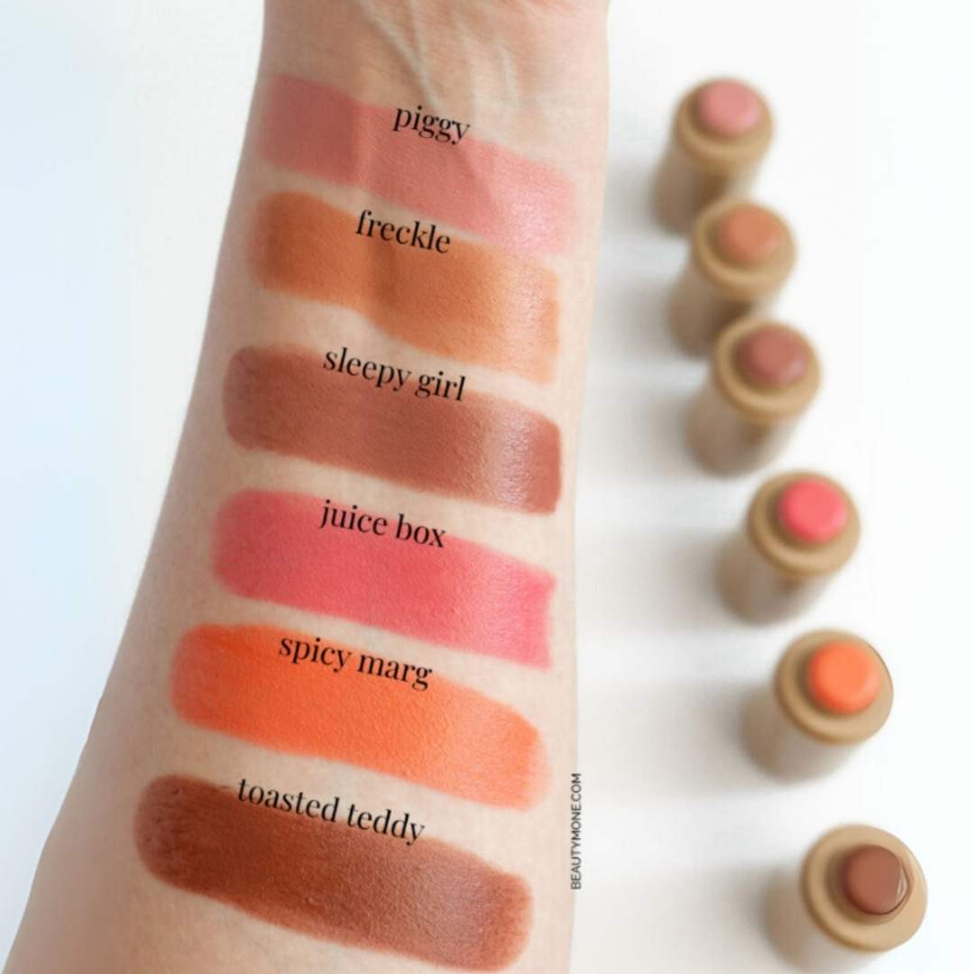 Lipstick swatches on a arm with labeled colors and lipstick tubes on a white background