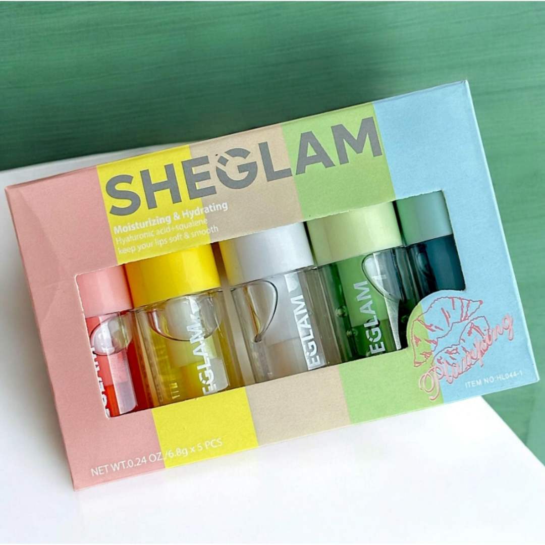 Sheglam skincare lip oil set with colorful packaging on a green background