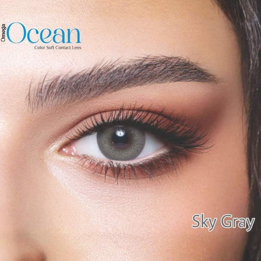Close-up of a person's eye wearing sky gray contact lenses with Omega Ocean branding.